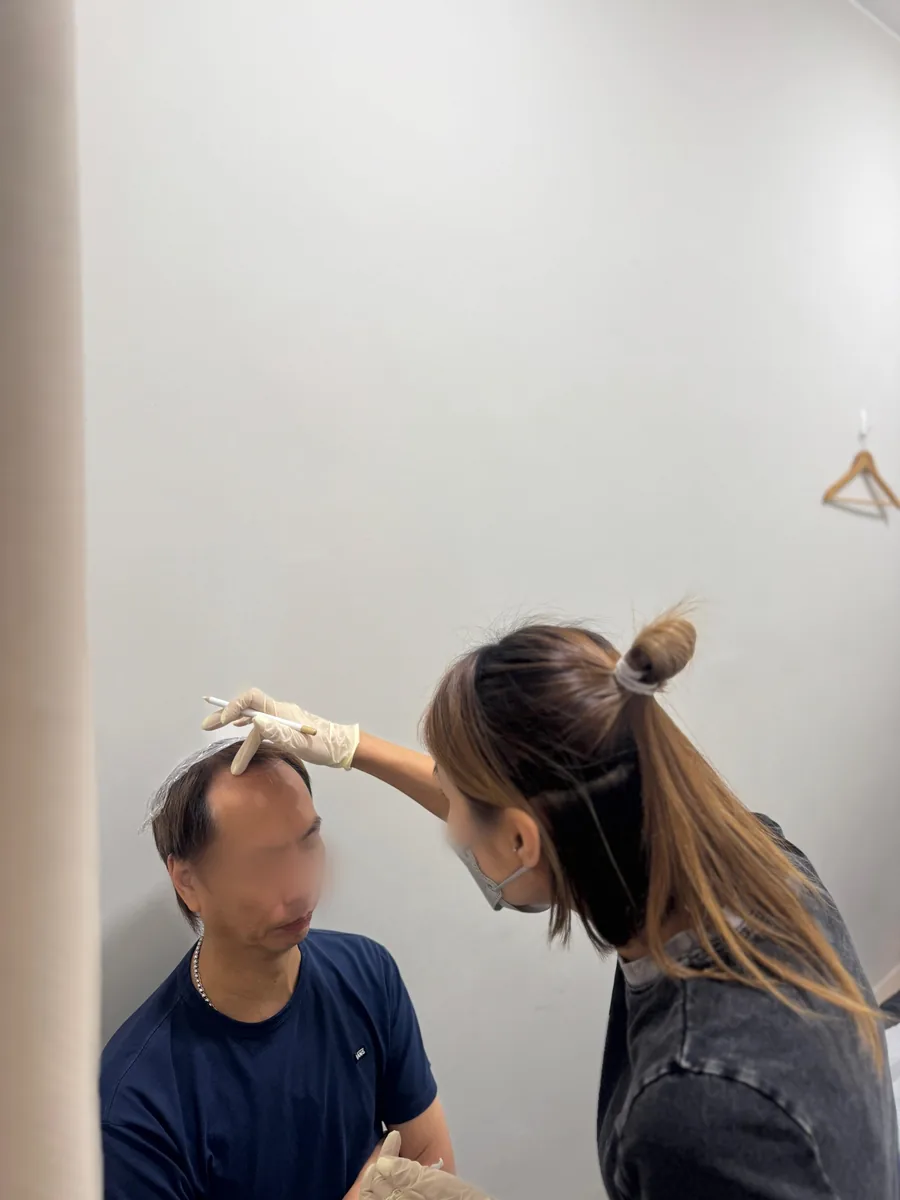 A student designing a male model's hairline